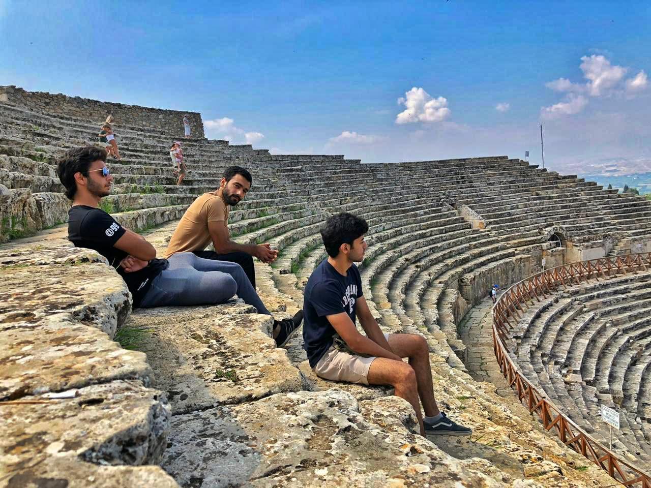 Founders seated along ancient amphitheater stone steps under open sky