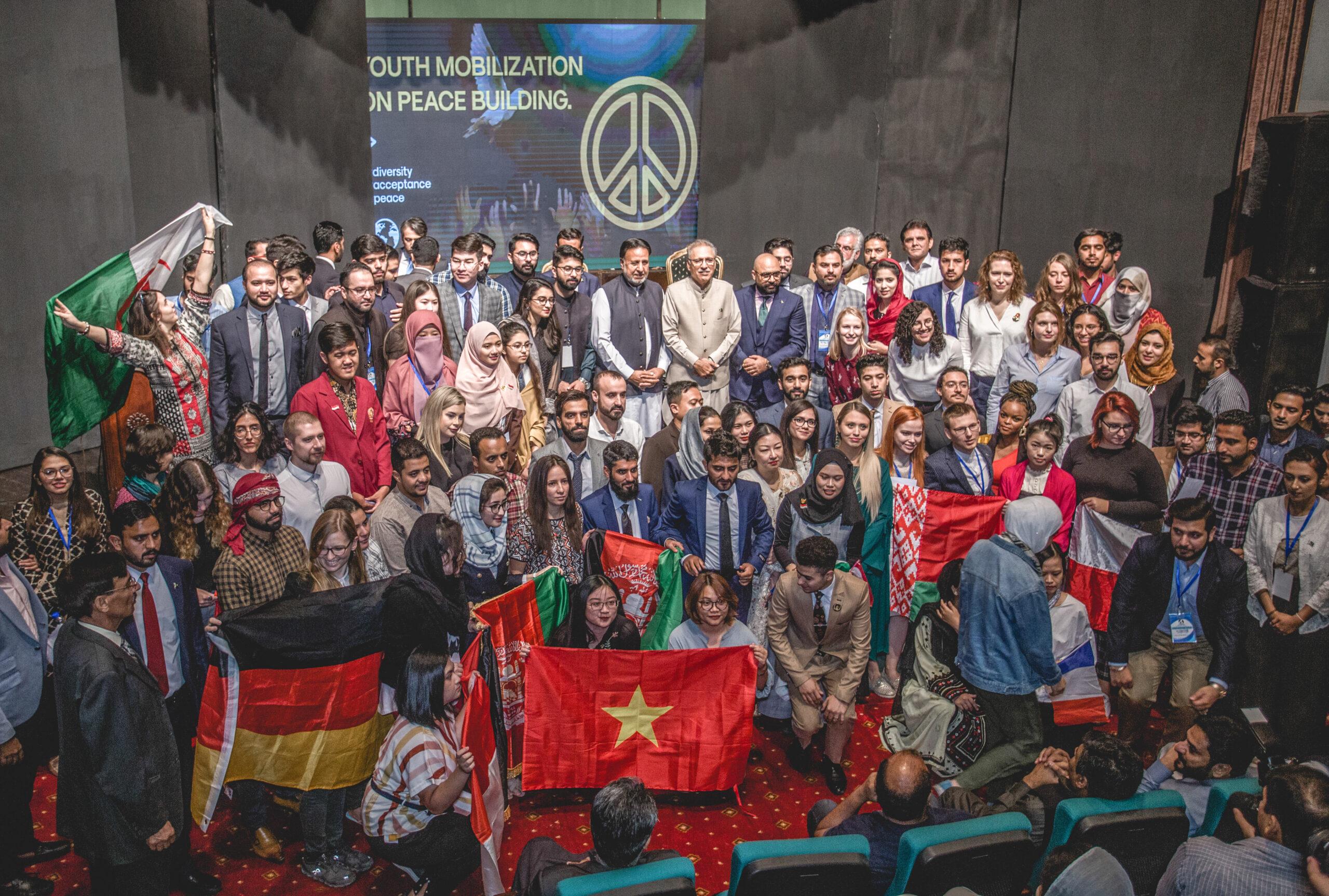 Large community group photo indoors with flags and banners