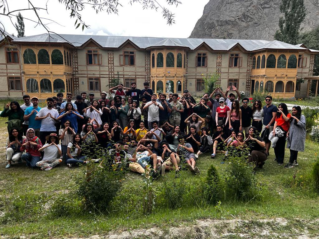 Large group posing on a mountain overlook under a blue sky