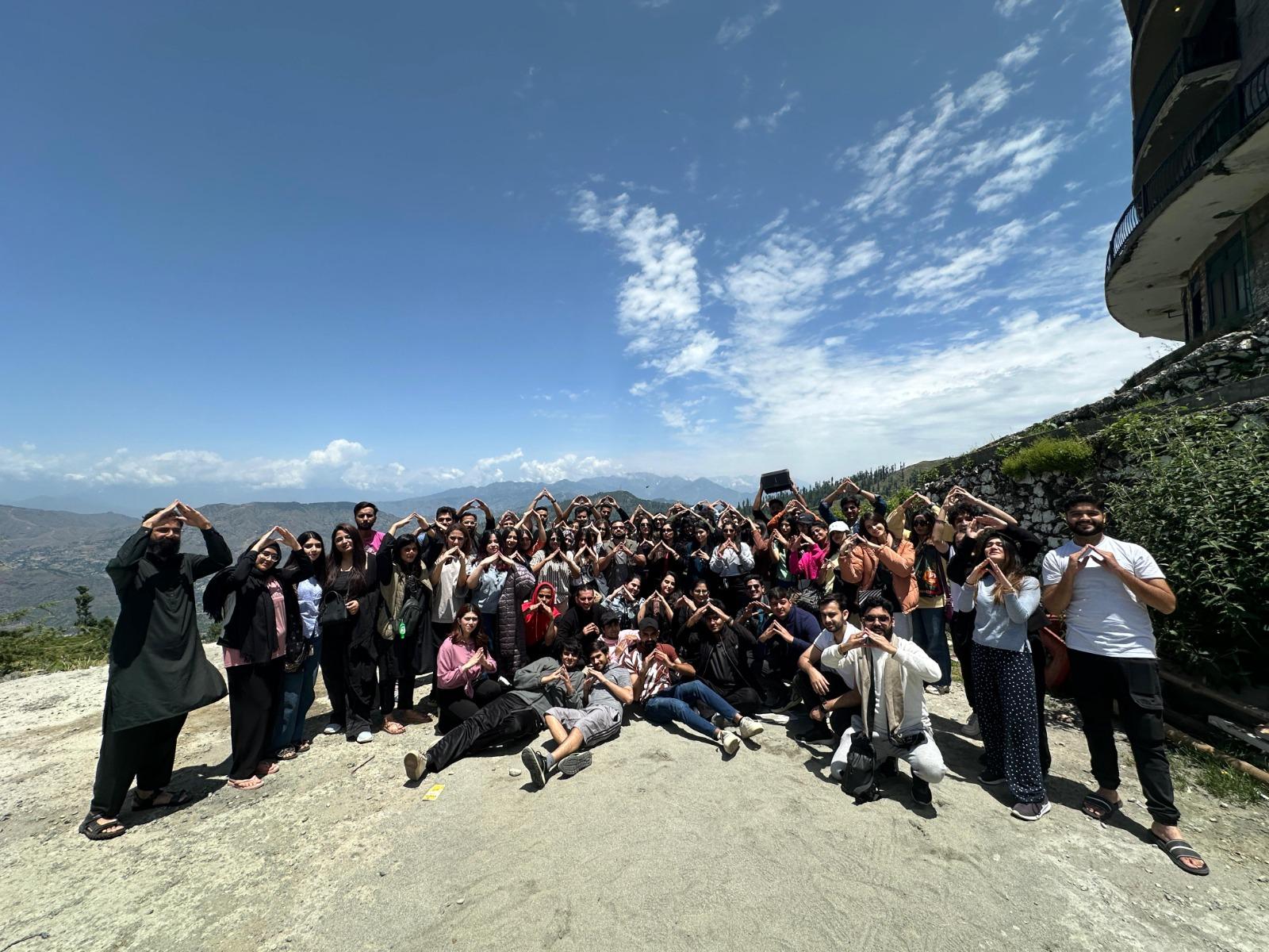 Group portrait with snow-capped mountains and a travel sign
