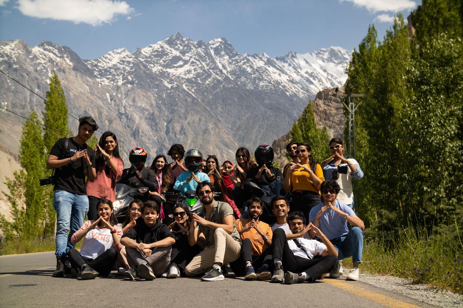Group seated by a scenic road with mountains and trees