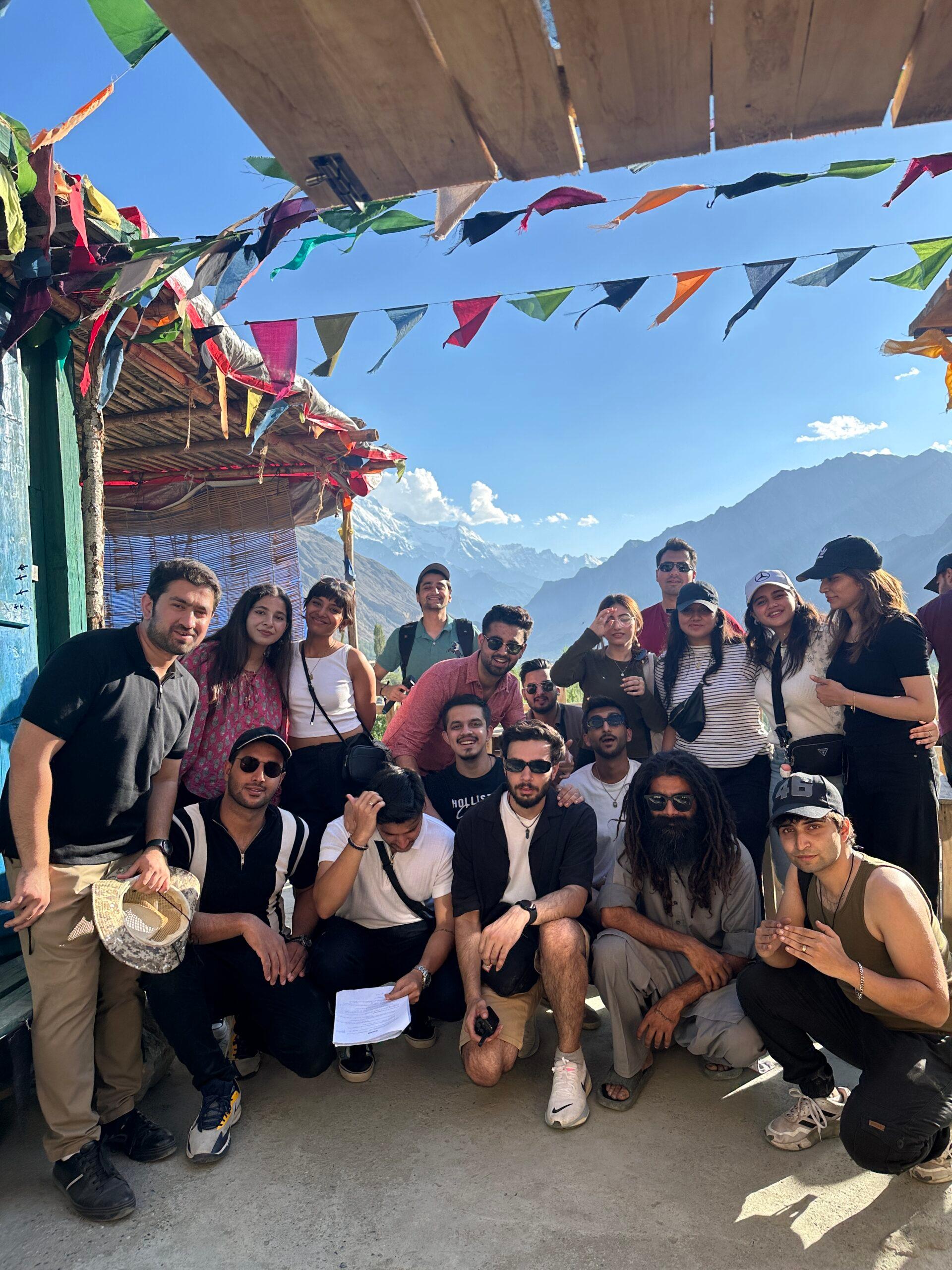 Travel group gathered on a hillside with flags and bright sky